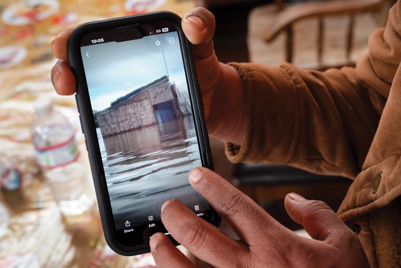 Nancy Nuñez shows a photo of a flooded structure on Picoso Farm. When the storm hit last March, they stored seedlings on its roof.