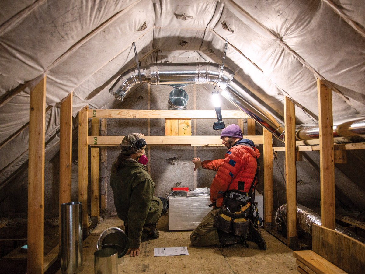 Cillian Liam Barrett and Edward Morrison install a heat pump system in the attic of a new accessory dwelling unit in Crested Butte, Colorado. The town recently passed new energy-efficient building codes.