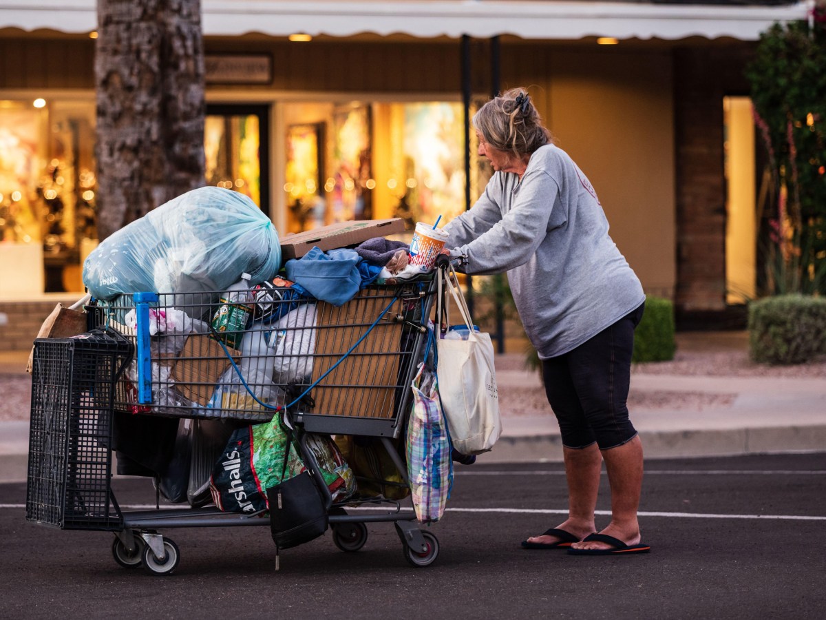 An unhoused woman pushes her belongings down the street in Scottsdale, Arizona. An Arizona initiative could force local governments to crack down on unhoused people or risk losing property tax revenue.