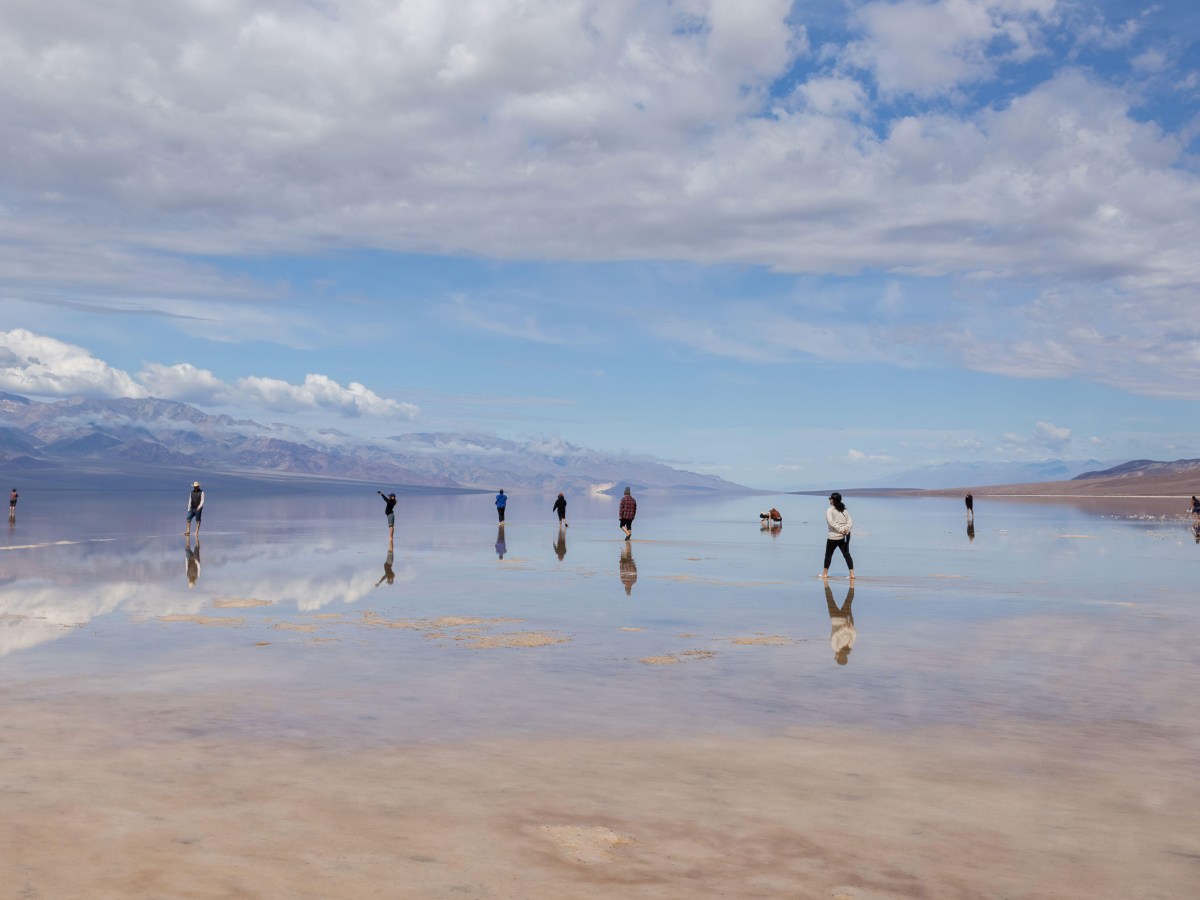 People wading in Lake Manly at Badwater Basin after a wet winter, Death Valley National Park, California.