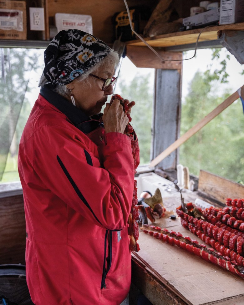 Katie Kangas in her smokehouse in Ruby, Alaska, and the view of the Yukon River from Katie and Ivan Kangas’ dining room.